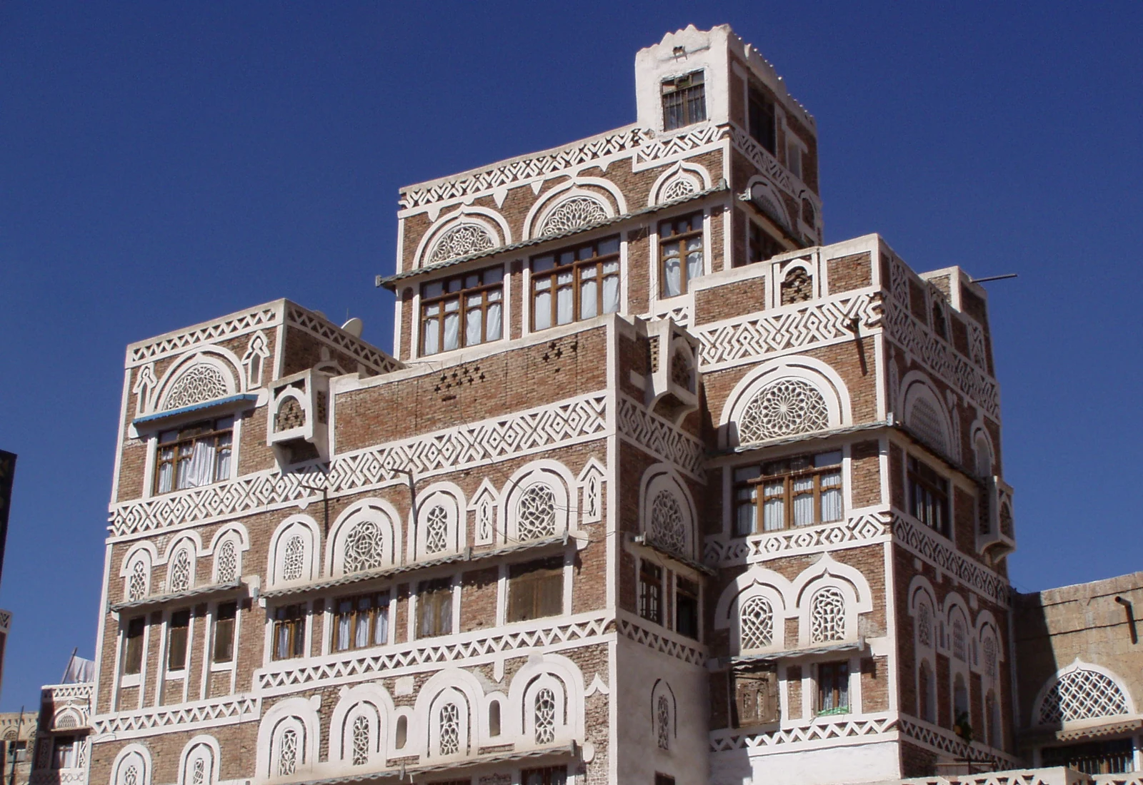 Traditional brick tower house with white decorative windows in the Old City of Sana’a